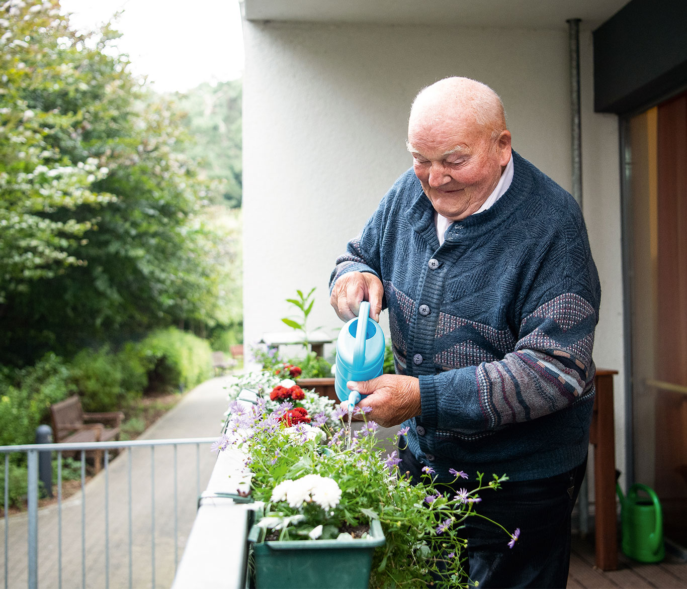 Mann gießt Blumen auf Balkon