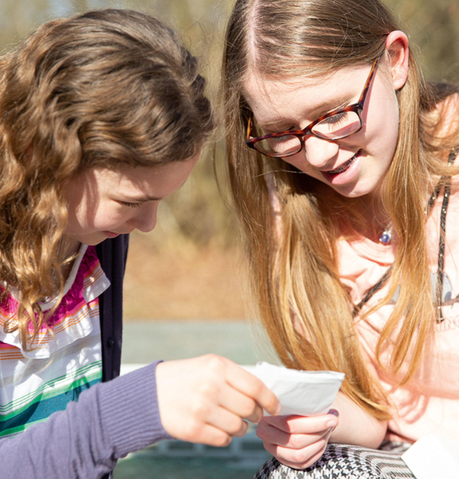 Zwei jugendliche Mädchen einer Wohngruppe der Vorwerker Diakonie schauen gemeinsam auf einen Zettel.