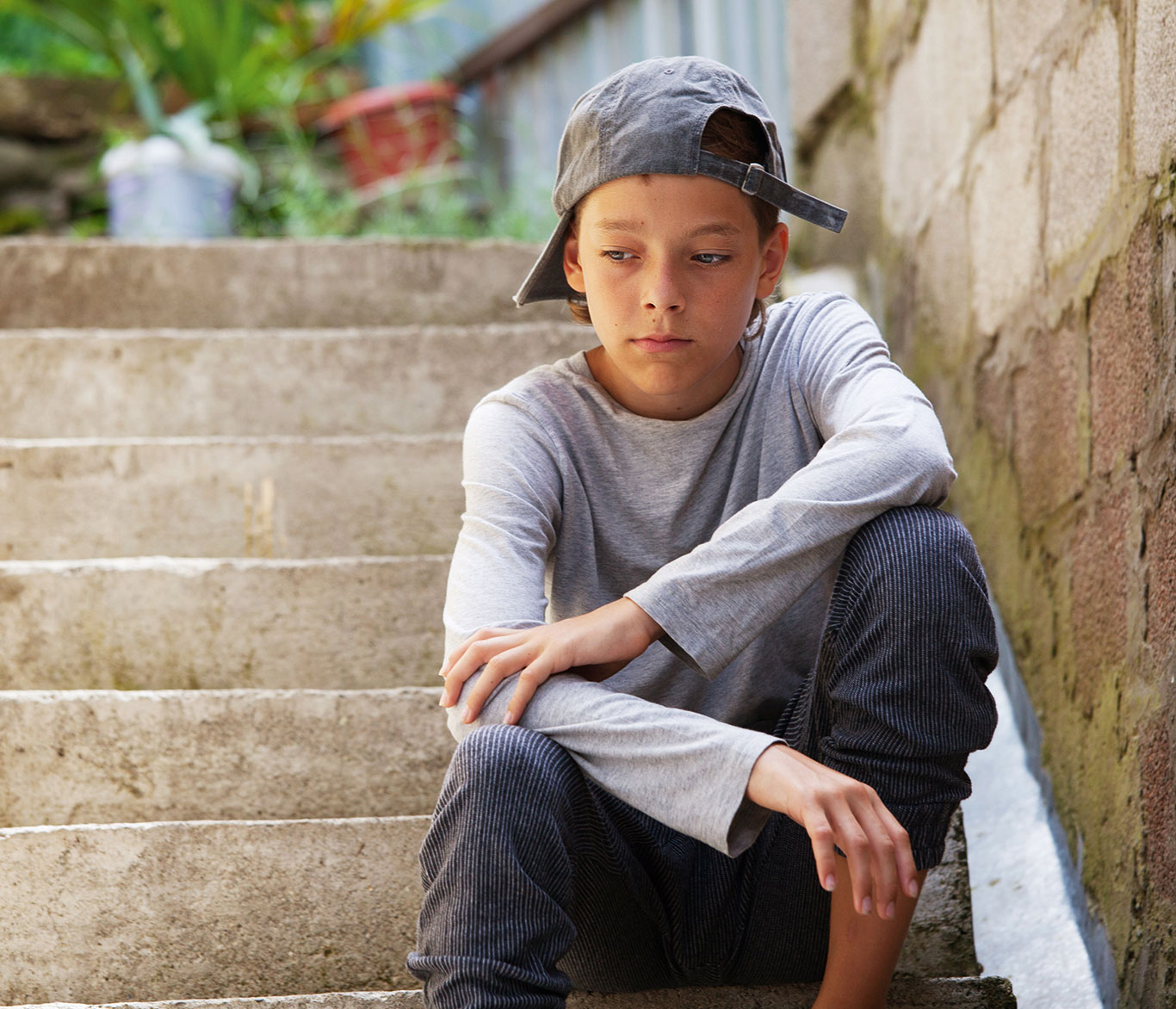 Ein Jugendlicher in einer Krise sitzt auf einer Treppe.