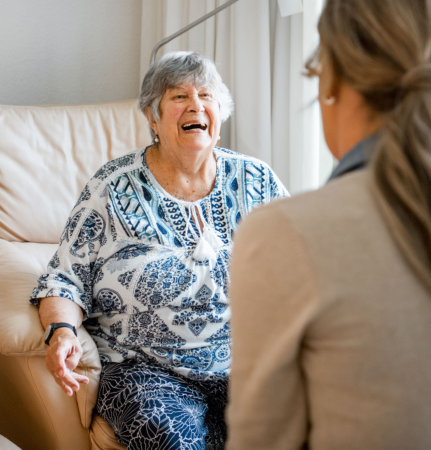 Eine pflegebedürftige Seniorin unterhält sich mit einer Pflegerin in einer Einrichtung der Seniorenpflege.