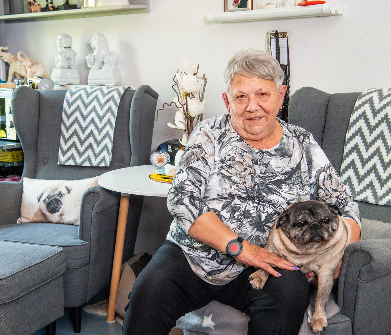 Pflegebedürftige Seniorin sitzt mit ihrem Hund in einer Einrichtung der Seniorenpflege.