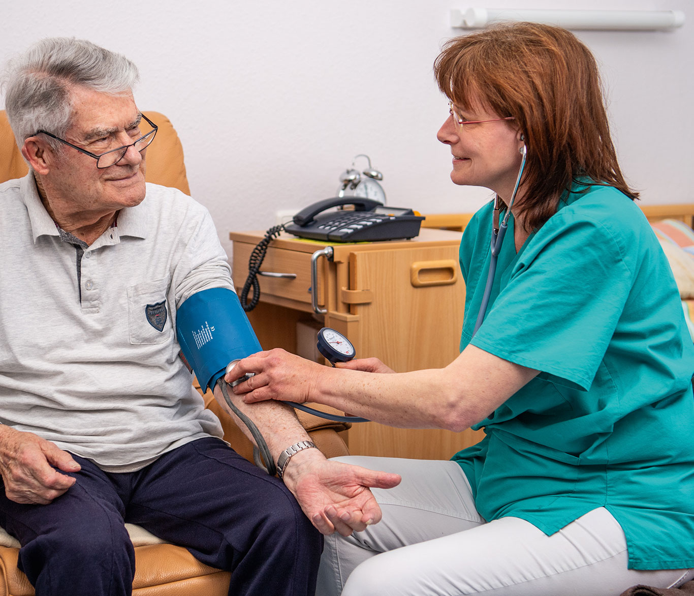 Pflegerin misst Senior in Einrichtung der Seniorenpflege den Blutdruck.