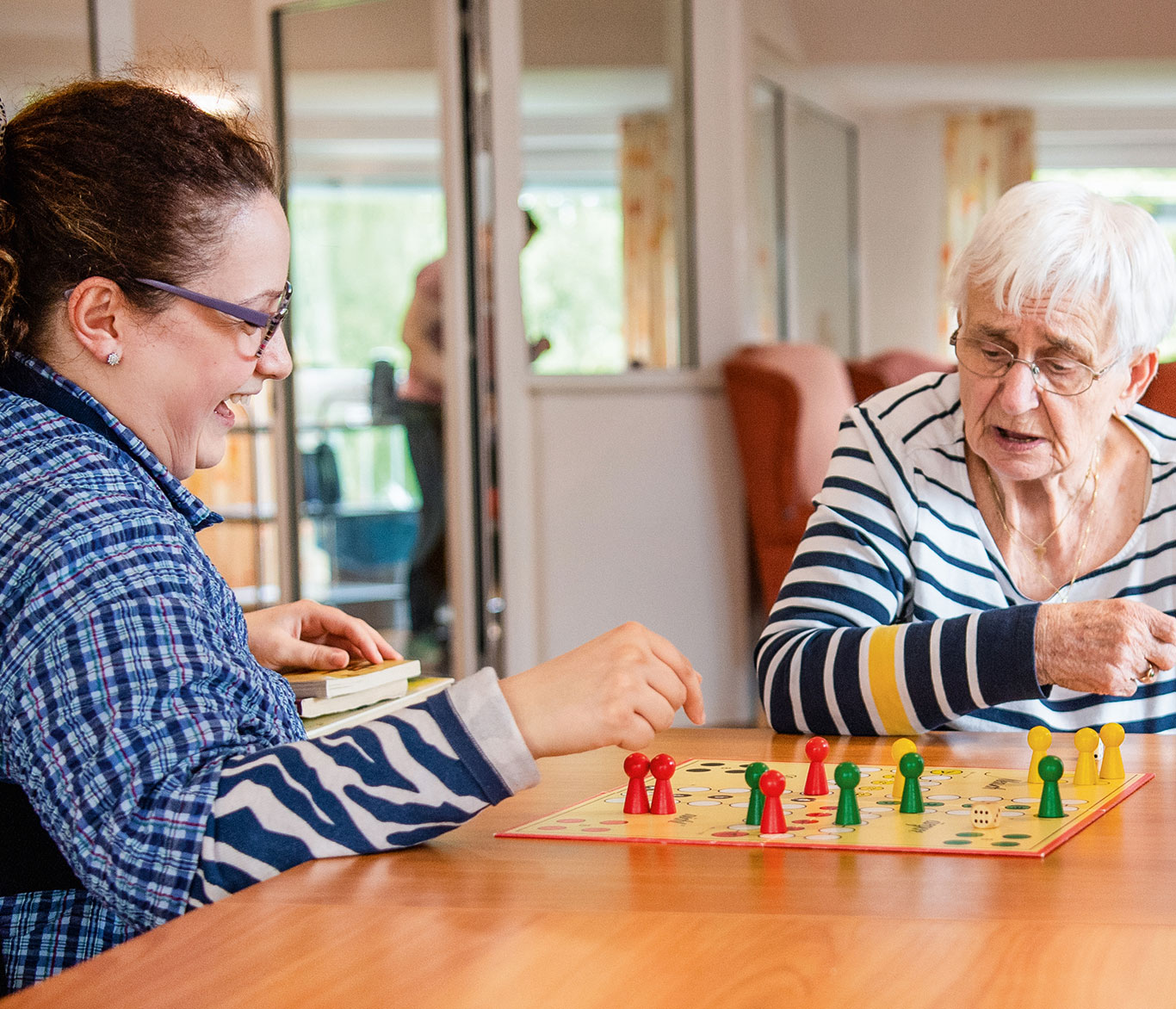 Eine Seniorin spielt mit Pflegerin ein Brettspiel in der Einrichtung für Seniorenpflege An der Georgskapelle in Bad Schwartau.