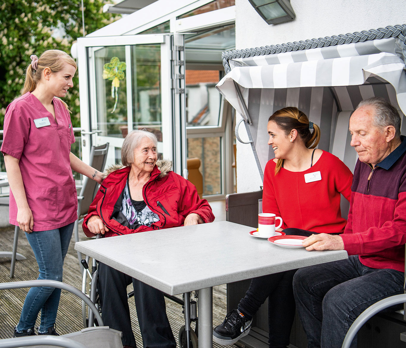 Pfleger und Senioren sitzen vor der Einrichtung der Seniorenpflege Georgskapelle in Bad Schwartau am Tisch.