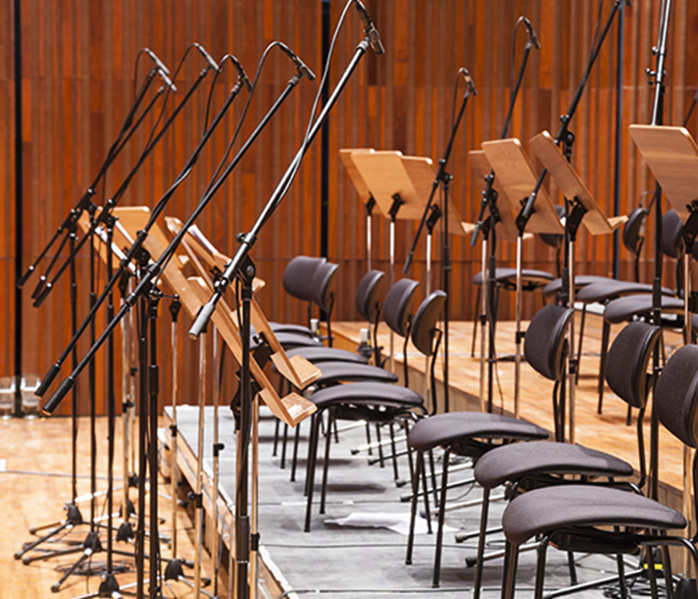 Mikrofone, Notenpulte und Stühle in einem Konzertsaal.
